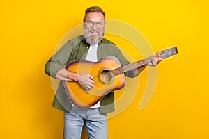 Portrait of funky granddad hold acoustic guitar playing song isolated on yellow color background