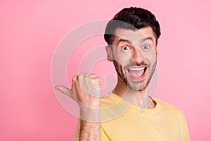 Portrait of funky impressed man stylish haircut yellow t-shirt indicating empty space open mouth isolated on pink color