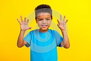 Portrait of funky small schoolboy with afro hair wear blue stylish t-shirt showing palms scare you  on vivid