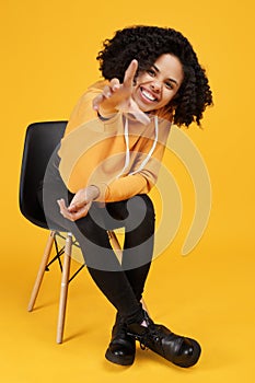 Portrait of funny african american young woman with beautiful smile dressed in casual clothes sitting on the stylish
