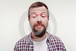 Portrait of funny awkward bearded man standing with crossed eyes, comic silly expression. isolated on white background