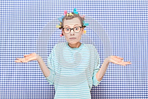 Portrait of funny bewildered girl with colorful hair curlers on head