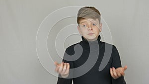Portrait of a funny blond and blue-eyed teenager boy showing condemnation with gestures and facial expressions on white