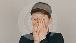 Portrait of a funny blond and blue-eyed teenager boy showing condemnation with gestures and facial expressions on white