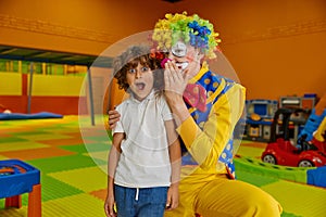 Portrait funny boy child and clown animator at indoor playground