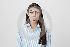 Portrait of funny caucasian female curling tongue while staring at camera acting childish over gray background