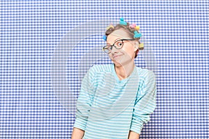 Portrait of funny cheerful girl with colorful hair curlers on head