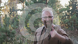 Portrait of a funny, cheerful man with glasses and a beard in the shape of a pigtail. Man raises his thumb up and shows