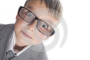 Portrait of a funny child boy wearing glasses against a white background. Smart child in suit and glasses looking at camera. Back