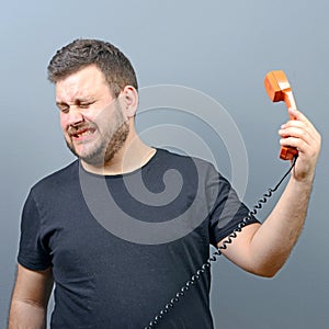 Portrait of funny chubby man in shock while talking on phone having unpleasant conversation against gray background