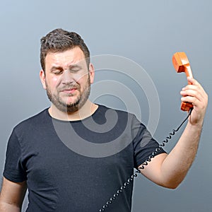 Portrait of funny chubby man in shock while talking on phone having unpleasant conversation against gray background