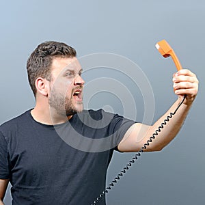 Portrait of funny chubby man shouting on phone against gray background