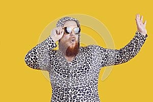 Portrait of funny comic chubby man who is strangely dressed and having fun on orange background.