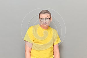 Portrait of funny confused mature man with glasses, with frowning face