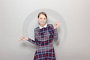 Portrait of funny confused young blond woman wearing checkered dress