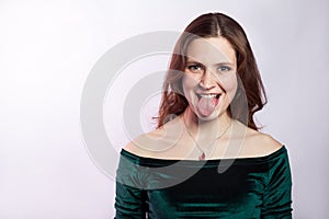 Portrait of funny crazy woman with freckles and classic green dress with tongue.