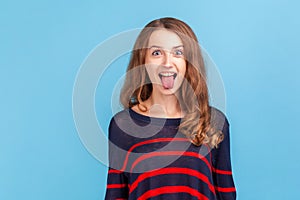 Portrait of funny disobedient young woman wearing striped casual style sweater demonstrating tongue