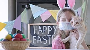 Portrait of funny Easter kid in bunny ears and mask with red cat