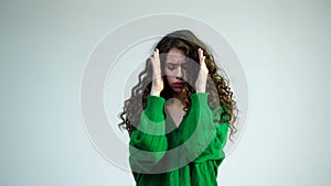 Portrait of funny emotional woman with braces on white background. Girl hides her eyes with her hands dressed in green