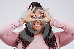 Portrait, funny face and finger mask with a black woman laughing in studio on a white background for humor. Comic