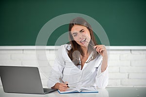 Portrait of a funny female student studying in school classroom. Female freelancer or a student with laptop computer.