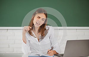 Portrait of a funny female student studying in school classroom. Female freelancer or a student with laptop computer.