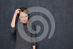 Portrait of funny focused puzzled woman scratching head with finger