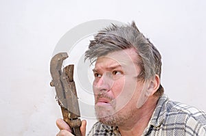 Portrait of a funny geezer with a rusty old dirty pipe wrench