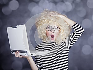 Portrait of funny girl in blonde wig with laptop. Studio shot.