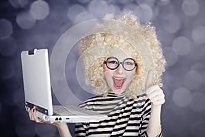 Portrait of funny girl in blonde wig with laptop.