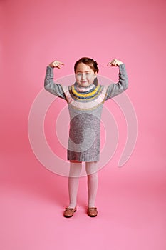 Portrait of funny girl showing to themself in warm dress on rosa background