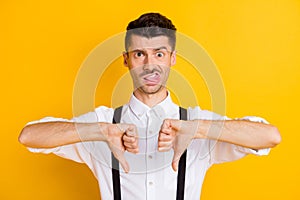 Portrait of funny guy wearing white shirt showing double thumb down disrespect isolated over bright yellow color
