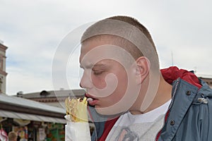 Portrait of a funny guy who eats shawarma with pleasure