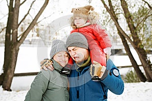 Portrait of funny happy family with one sad toddler in winter sporty outfit walking outdoors