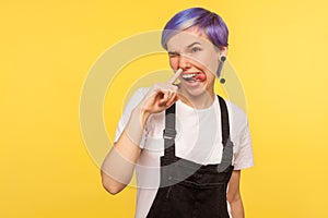 Portrait of funny impolite hipster girl making crazy face with tongue out and picking her nose. studio shot, indoor
