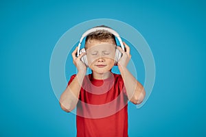 Portrait Of Funny Little Boy Listening Music In Wireless Headphones