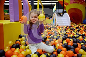 Portrait of funny little girl child playing in ball pit