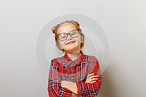 Portrait of a funny little preschool child girl in glasses on gray background. Concept education. Back to school