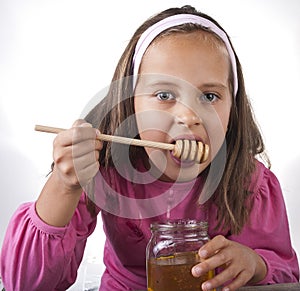 Portrait of funny lovely little girl eat honey