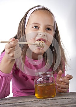 Portrait of funny lovely little girl eat honey