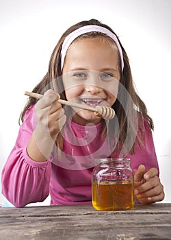 Portrait of funny lovely little girl eat honey