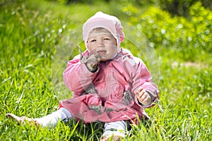 Portrait of funny lovely little girl sitting on a green grass