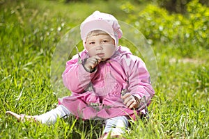 Portrait of funny lovely little girl sitting on a green grass