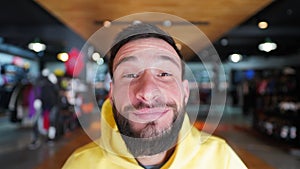 Portrait of a funny man with a black beard in a yellow jacket with a hood