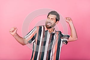 Portrait of funny mature man wearing striped shirt raised fists up chill out discotheque in summer isolated on pink