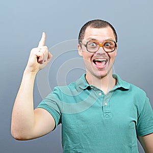 Portrait of funny nerd guy having an idea against gray background