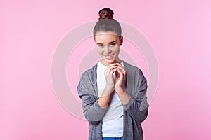 Portrait of funny playful brunette teenage girl grinning at camera with cunning sly expression. studio shot pink background