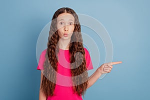 Portrait of funny positive small lady indicate finger blank space reacting novelty on blue background