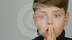 Portrait of a funny red-haired teen boy with blue eyes and freckles who is surprised on a white background in studio