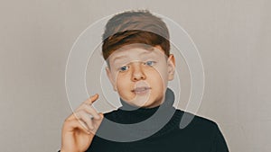 Portrait of a funny redhead and blue-eyed teenager boy showing condemnation with gestures and facial expressions on